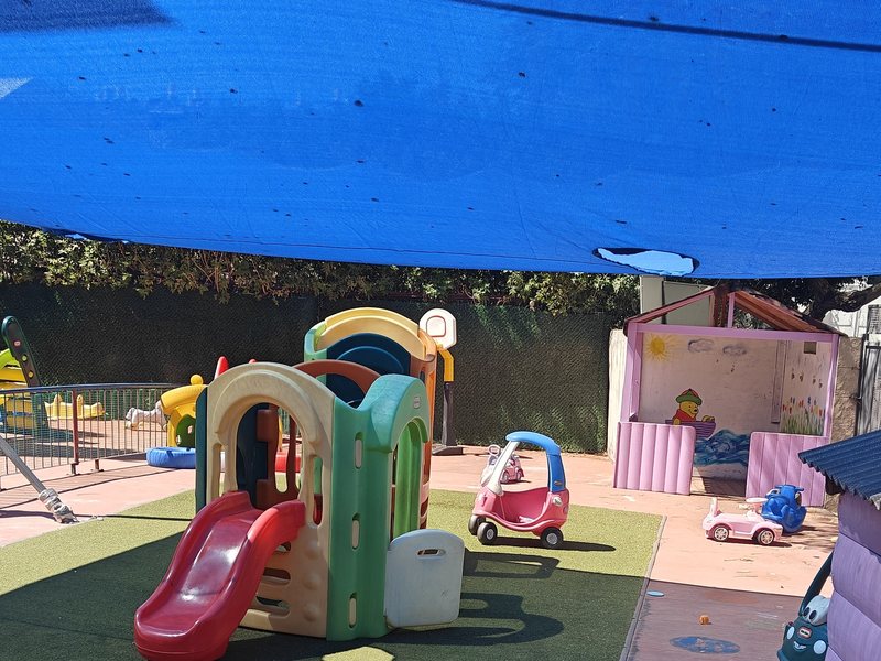 החצר מזווית שנייה — מתקן הטיפוס ומכוניות משחק